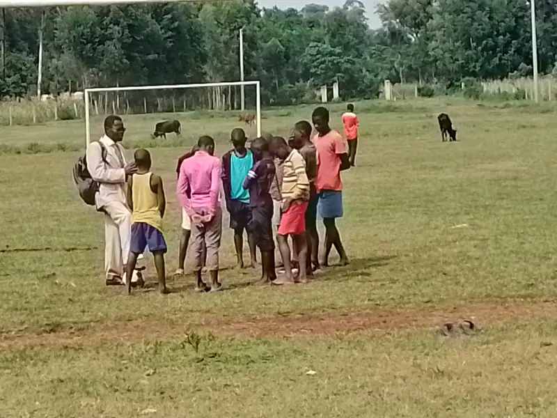 A teacher with a group of children on an open field
